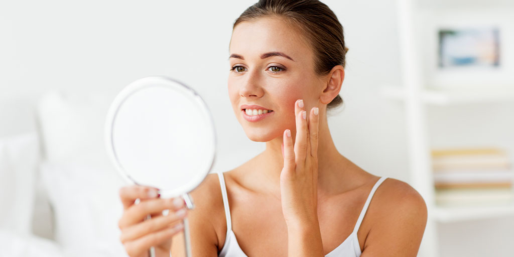 Woman looking at skin in the mirror