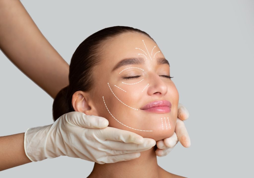 Beauty Treatment. Calm girl receiving face massage from cosmetologist who wearing protective gloves, isolated