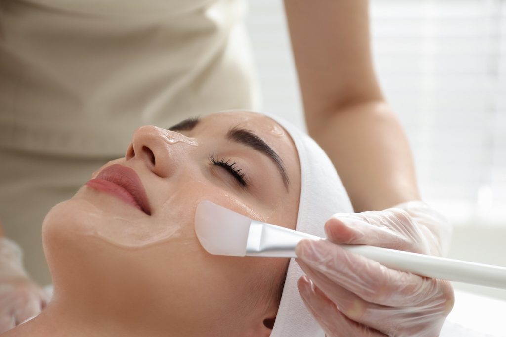 Young woman during face peeling procedure in salon