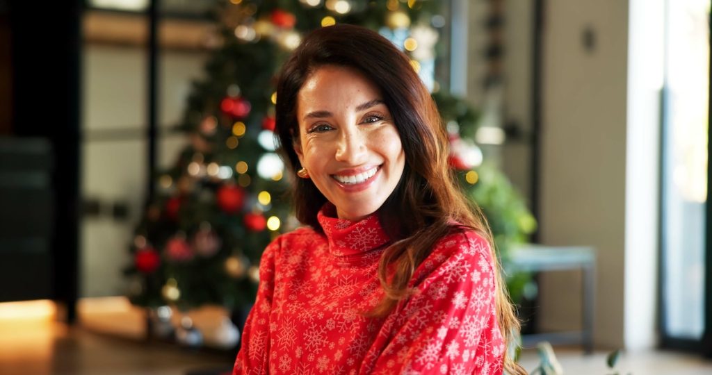 Portrait, smile and woman with Christmas in home, holiday happiness and festive season in December. Xmas time, positive spirit and excited mature person with winter sweater, vacation and decorations