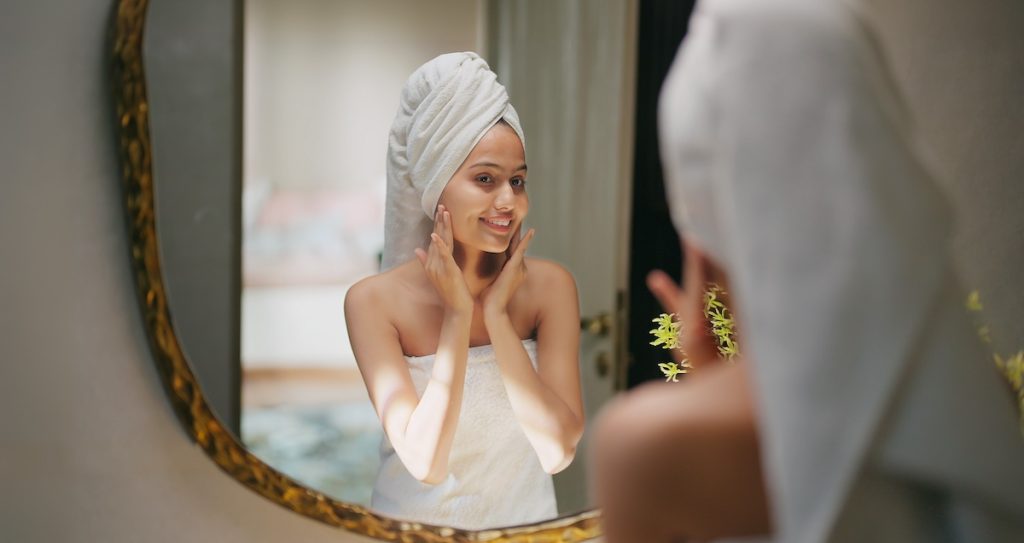 woman in bathroom mirror doing skincare routine in the new year with fresh-skin